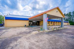 a building with an american flag in a parking lot at Economy Inn By Townhouse Livingston TX Hwy 59 in Livingston