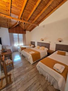 a room with three beds in a room with wooden ceilings at Hotel Bahía in Puerto San Julian