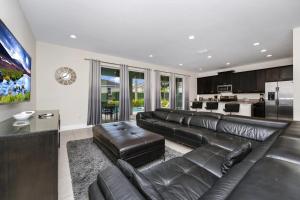 a living room with a leather couch and a kitchen at Charming Home Near Disney With Game Room And Waterpark & Resort Access At Encore Resorts Reunion - 7592Mr in Kissimmee