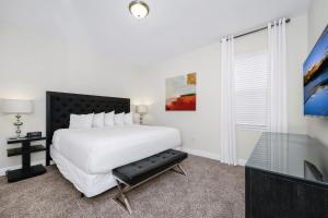 a white bedroom with a bed and a tv at Charming Home Near Disney With Game Room And Waterpark & Resort Access At Encore Resorts Reunion - 7592Mr in Kissimmee