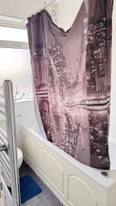 a bath tub with a shower curtain in a bathroom at Panthea Home in Barkingside