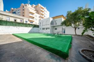 ein Tennisplatz mit grünem Boden auf einem Parkplatz in der Unterkunft Plaza Inn Hostel & Rooms in Faro