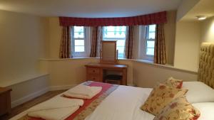 a bedroom with a bed and two windows at Mayville House Flat in Cheltenham