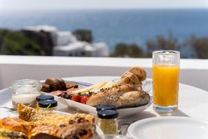 a table with a plate of food and a glass of orange juice at Red Beach Harmony suites Modestos in Akrotiri
