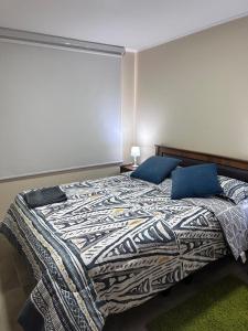 a bedroom with a large bed with blue pillows at Departamento en Linares in Linares