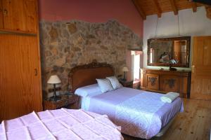 a bedroom with two beds and a stone wall at La casa del agua Cantabria in Ampuero