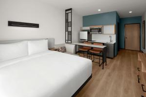 a hotel room with a white bed and a kitchen at StudioRes by Marriott Fort Myers Airport in Miromar Lakes