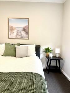 a bedroom with a bed and a table at 500m to Werri Beach - The Palms in Gerringong