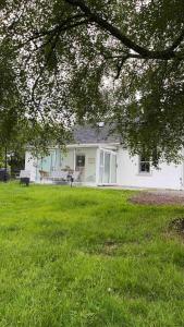 a white house with a green lawn in front of it at Horseshoe Cottage, Killarney in Killarney