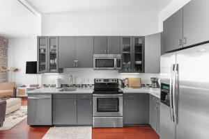 a kitchen with gray cabinets and stainless steel appliances at Downtown Loft- Steps away from Plant Riverside! in Savannah