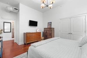 a bedroom with a bed and a dresser and a television at Downtown Loft- Steps away from Plant Riverside! in Savannah +14 photos
