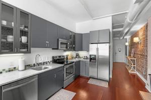 a kitchen with gray cabinets and stainless steel appliances at Downtown Loft- Steps away from Plant Riverside! in Savannah