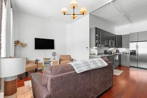 a living room with a couch and a kitchen at Downtown Loft- Steps away from Plant Riverside! in Savannah