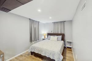 a white bedroom with a bed and a window at Beach Bungalow Getaway in Michigan City