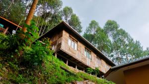 a wooden house on a hill with trees in the background at Rushaga Gorilla Lodge in Bugambira