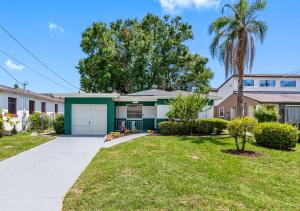 a house with a green garage and a palm tree at Stunning Tampa Stay - Prime Location & Comfort in Tampa