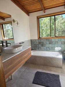 a bathroom with a tub and a sink and a window at Thrums Bush Retreat in Upper Orara