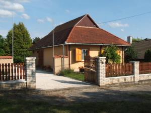 ein Haus mit einem Holzzaun davor in der Unterkunft Zsiga Apartmanház in Balatonszabadi