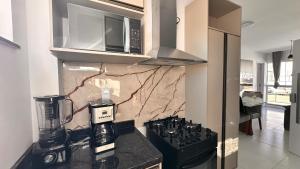 a kitchen with a stove and a microwave at Dona Olivia Universidade in Vitória da Conquista