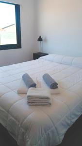 Una cama blanca con dos toallas y una ventana. en Luna Escandalosa, en San Rafael