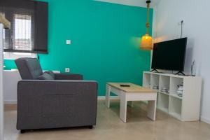 un salon avec un canapé, une table et une télévision dans l'établissement Apartamentos rurales ataecina, à Alcuéscar