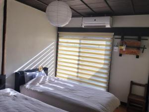 a bedroom with two beds and a window with blinds at 古民家クルンズ in Mino