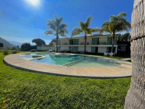 a pool in front of a building with palm trees at Hotel Brisas Del Lago in Valle de Bravo