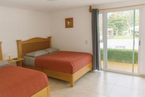 a bedroom with two beds and a sliding glass door at Hotel Brisas Del Lago in Valle de Bravo