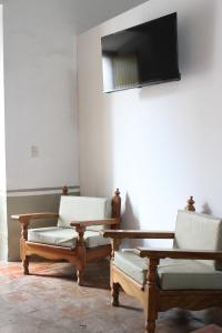 a room with two chairs and a table and a television at Hospedaje la gran Tenochtitlán in San Martín Hidalgo
