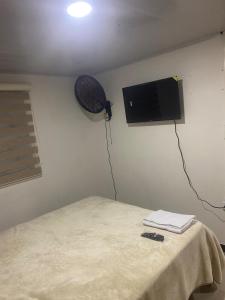 a room with a bed and a television on a wall at FInCA LA BENDICIÓN DE SUNNYVALE in La Vega
