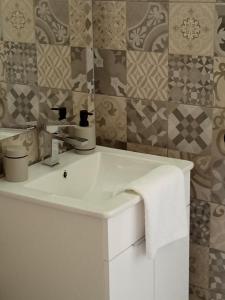 a white sink in a bathroom with tiles at Apartmani Piralis in Bihać +8 photos