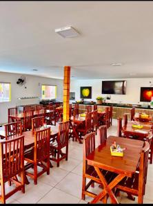 a restaurant with wooden tables and chairs and a television at Viana Praia Hotel e Restaurante- Pontal do Peba-Piaçabucu in Piaçabuçu +71 photos
