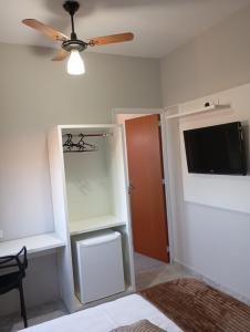 a bedroom with a ceiling fan and a tv at Village Prime in Inocência