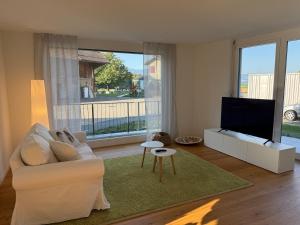 a living room with a white couch and a flat screen tv at Landluft in Stadtnähe in Rapperswil-Jona