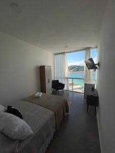 a bedroom with a bed and a view of the ocean at Pousada Mirante do Atalaia - Praia da Escadaria - Arraial do Cabo in Arraial do Cabo