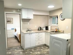 a kitchen with white cabinets and a bed in a room at Private Cozy 2bdrm Sleep5pp Metrotown! Free Parking! Self Check-in! in Burnaby