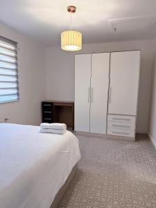 a bedroom with a large white bed and a chandelier at Modern Home with Private Garden and Car Park in Manchester in Little Hulton +20 photos