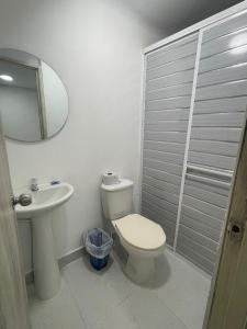 ein Badezimmer mit Toilette, Waschbecken und Spiegel in der Unterkunft Hotel Lago Cartagena in Estación El Salto