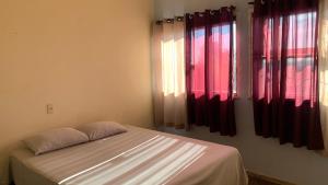 Cama en habitación con cortinas rojas en Hostel Aruanda, en Belo Horizonte