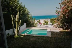 a swimming pool with a cactus and the ocean at Écrin bleu - Vue mer & piscine in Tunis