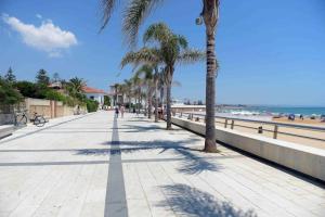 a sidewalk next to the beach with palm trees at Il Mare a Pochi Passi in Marina di Ragusa