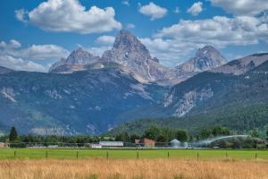 a view of a mountain range with a field and mountains at Panoramic Teton Views - Hot Tub - Theater Room in Driggs