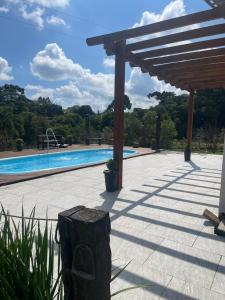 a wooden pergola next to a swimming pool at Chácara de lazer Mandirituba in Rio da Várzea