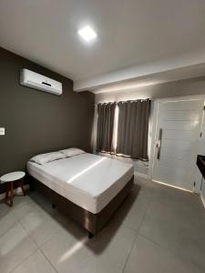 a bedroom with a large bed and a window at Apartamento na Praia da Vila in Imbituba