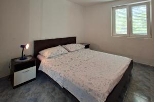 a bedroom with a bed with a nightstand and a window at Apartments with parking space Zaglav, Dugi otok - 11924 in Zaglav