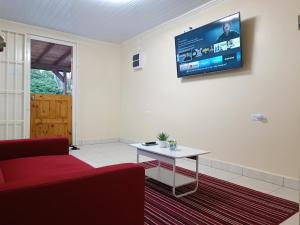 a living room with a red couch and a tv on the wall at Elite Visitors Aruba in Oranjestad