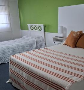 a bedroom with two beds and green walls at Alojamiento Passiflora I in Villa Elisa +6 photos