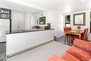 a kitchen with white cabinets and a dining room with a table at Hill Cottage - Featherston Holiday Home in Featherston +21 photos