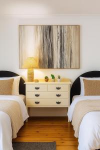 a bedroom with two beds and a dresser with a lamp at Fun Family Escape with Highland Cows in Medowie +23 photos