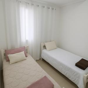 a bedroom with two beds with white and pink at Apartamento Familia Granja Viana in Carapicuíba